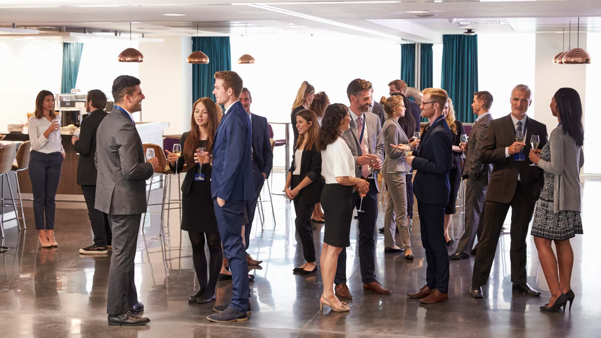 group of business people at a networking event standing, talking, and drinking