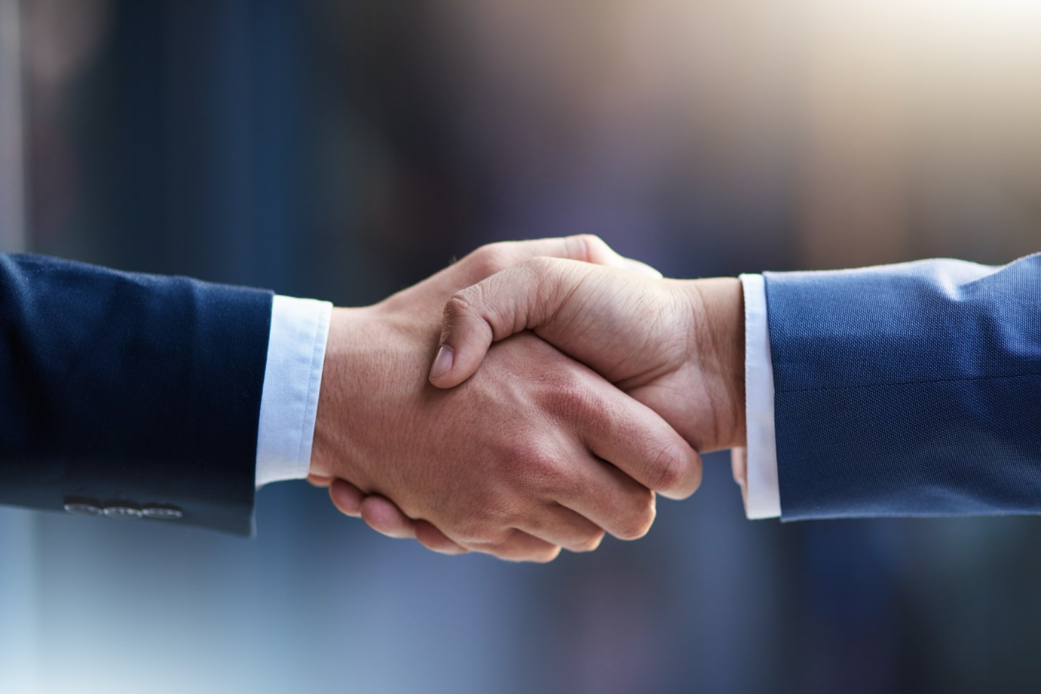closeup of two businessmen in suits shaking hands