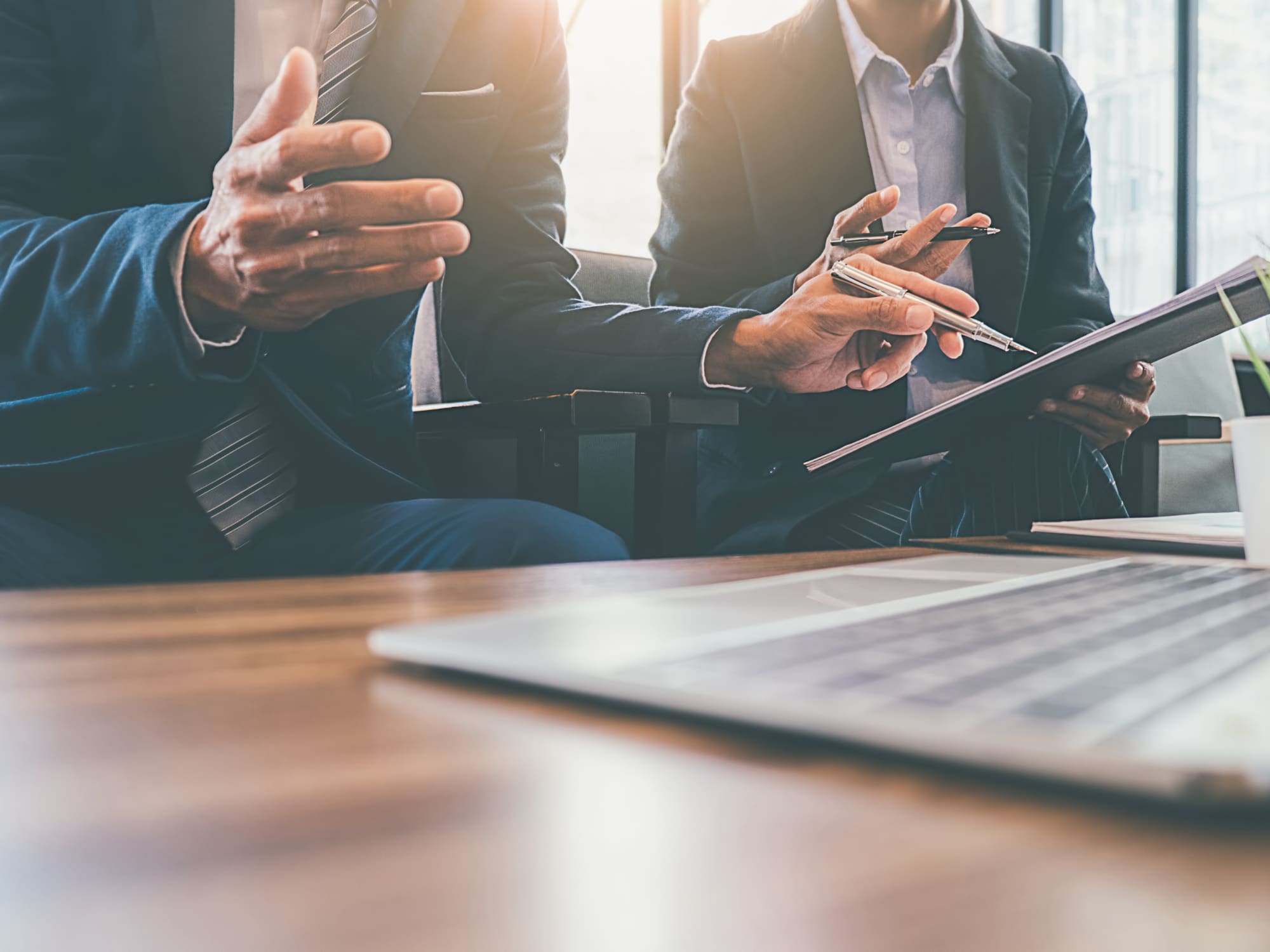 Close up of two business people looking over contract with pens in their hands
