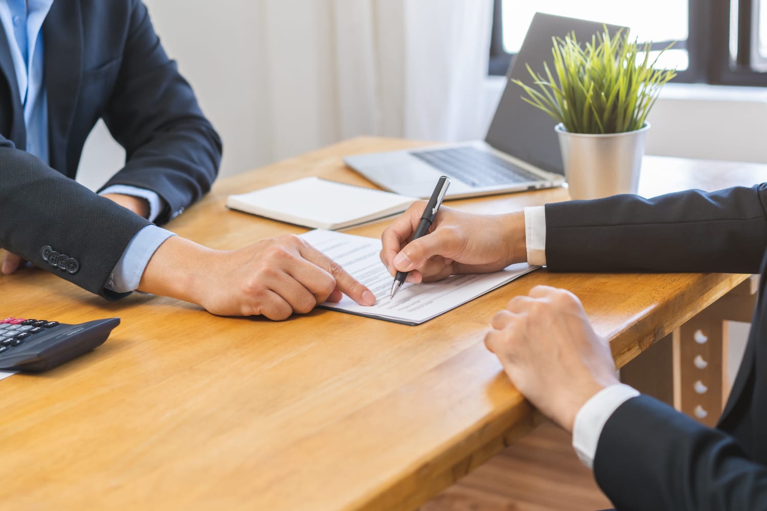 business people sitting at a wooden desk signing a contract